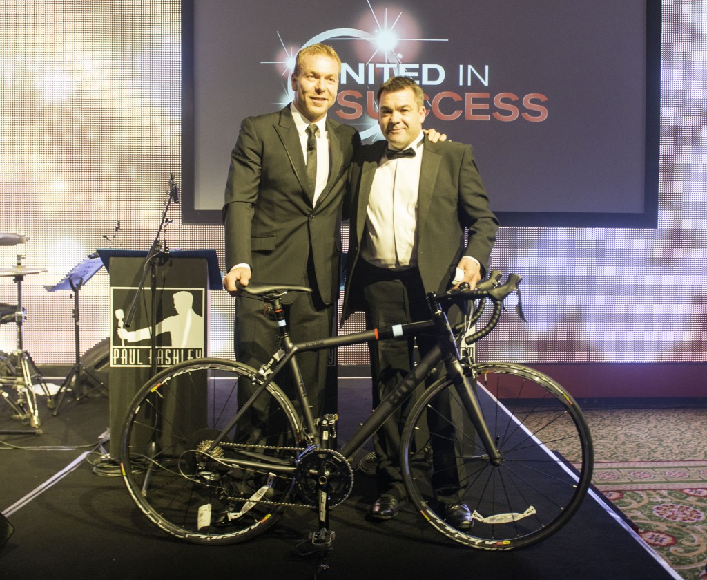 Olympic legend Sir Chris Hoy presents Tony Jordan, Dealer Principal at Dorchester Nissan, in Dorset, with the signed bike which is now being auctioned for charity