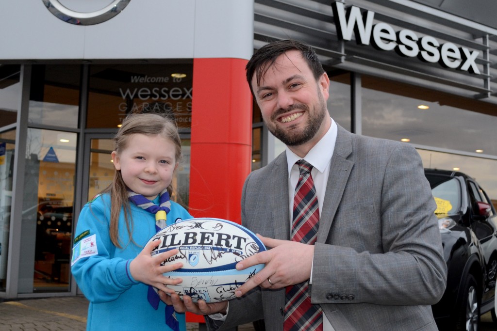 Seven-year-old Amelia Hayes collects the signed Cardiff Blues rugby ball from Gareth Howells, General Manager at Wessex Garages